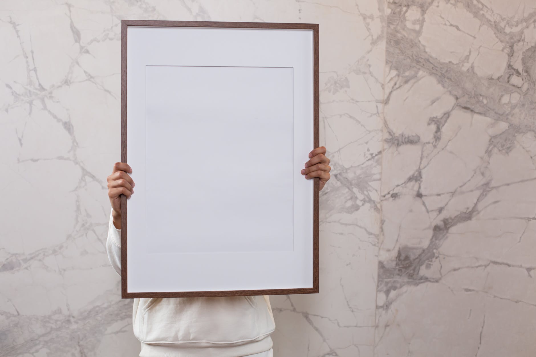 person showing large blank frame near wall with patterns